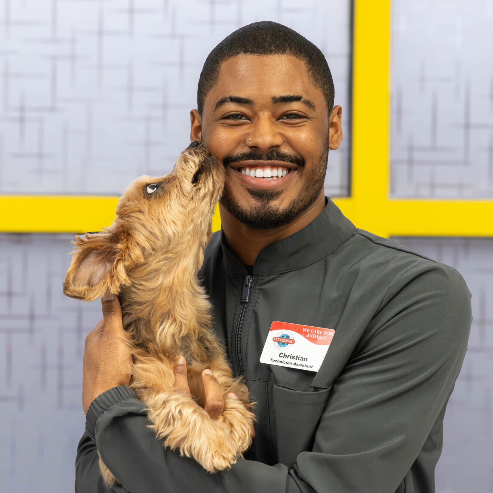 Christian Tech Assistant Man smiling holding light brown dog