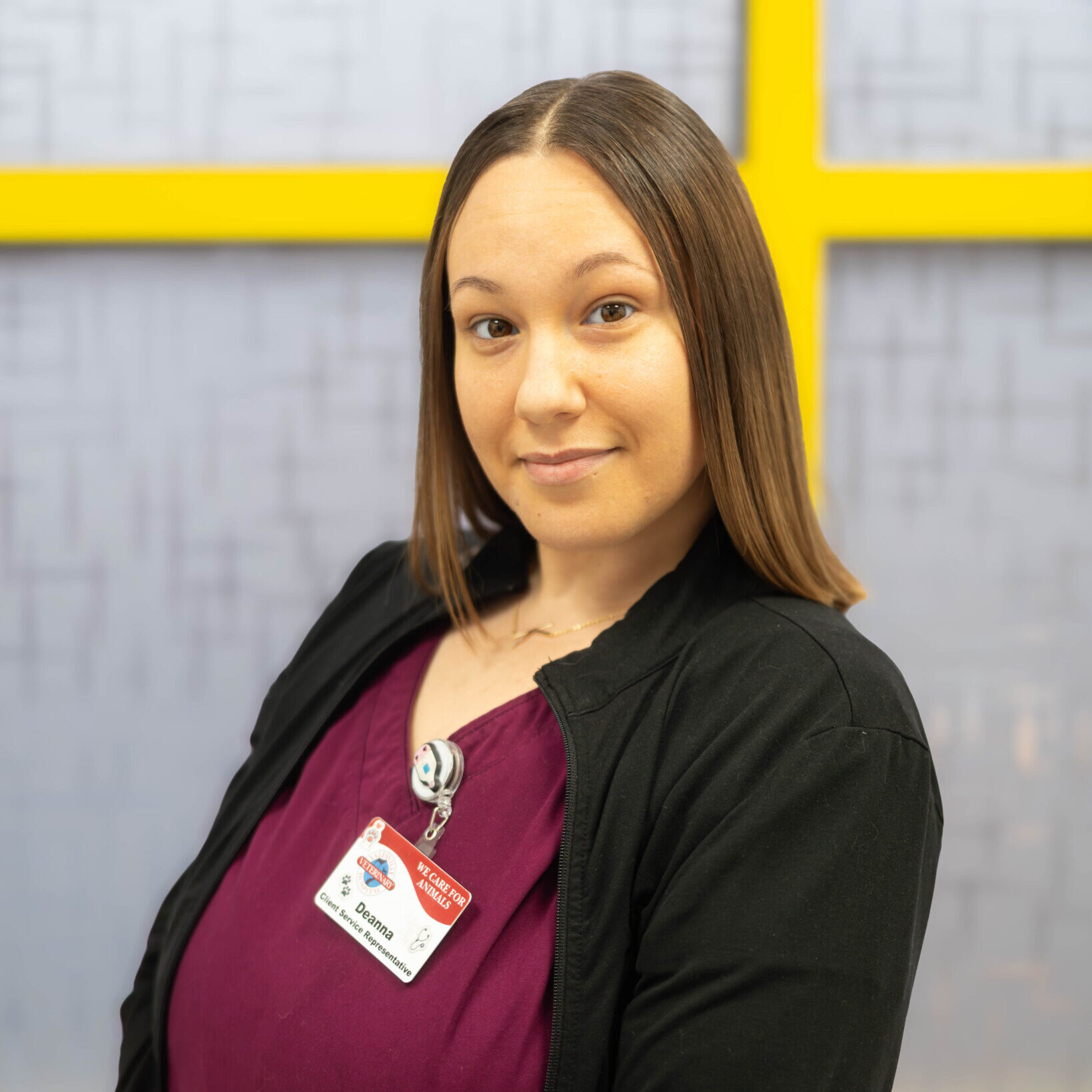 Brown haired woman in burgundy scrubs and black jacket