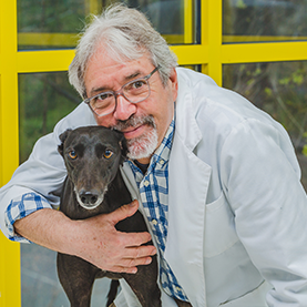 Frank Kostolitz DVM with arm around black dog