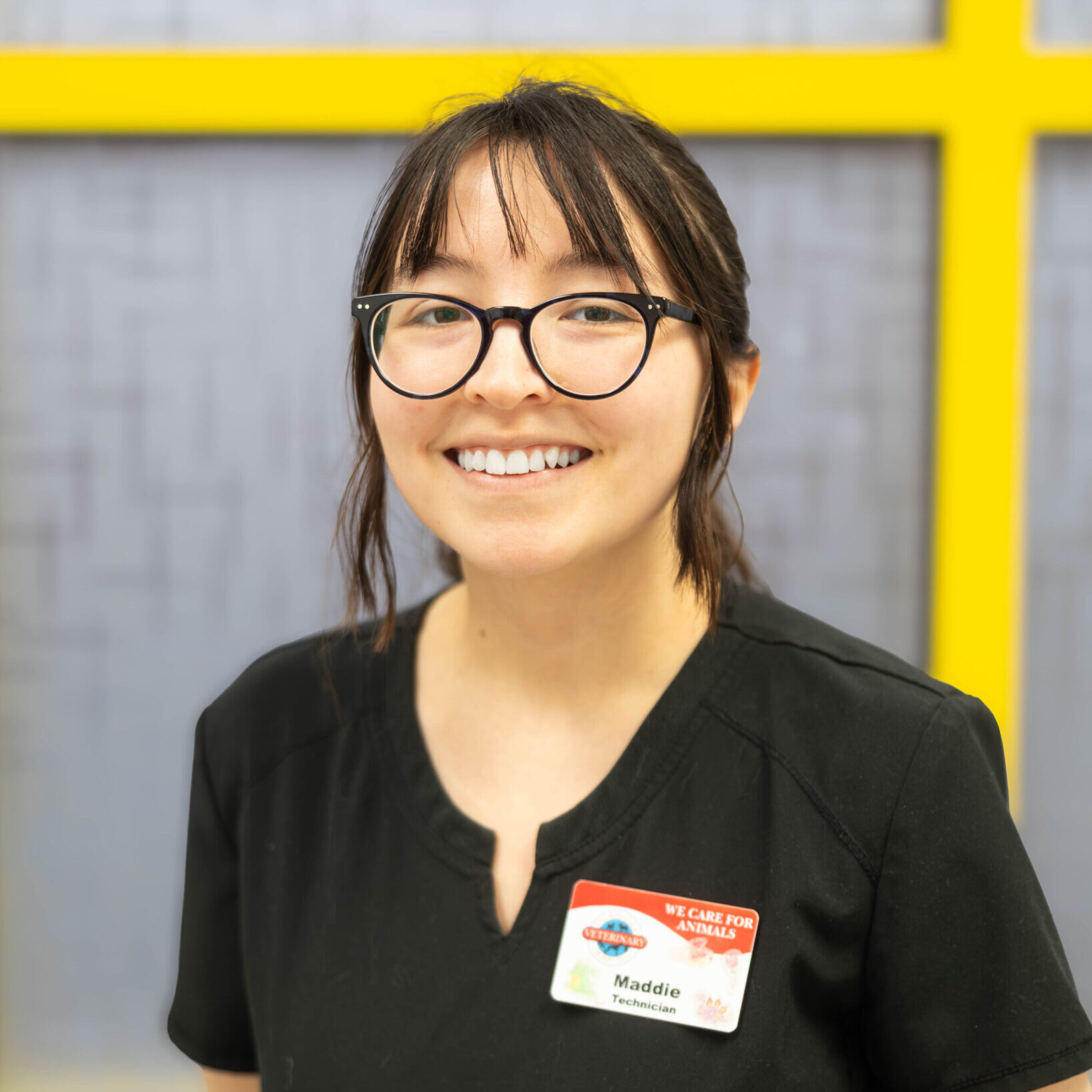 woman with glasses smiling in black scrubs